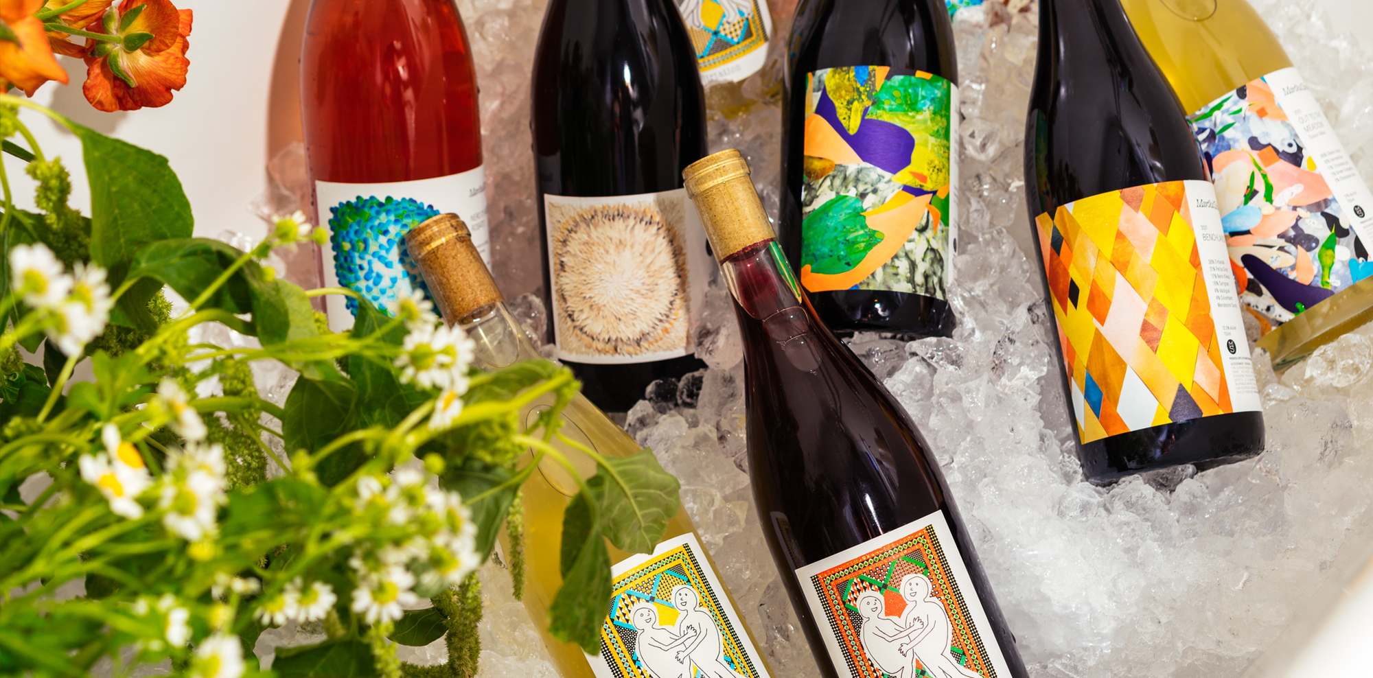 Bottles of red, white, and rosato Martha Stoumen Wines sit over ice with flowers in the corner