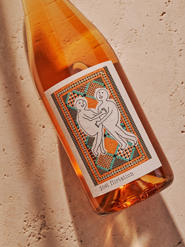A bottle of rosé wine with a colorful label featuring two playful figures and the text "post flirtation." The background is textured.