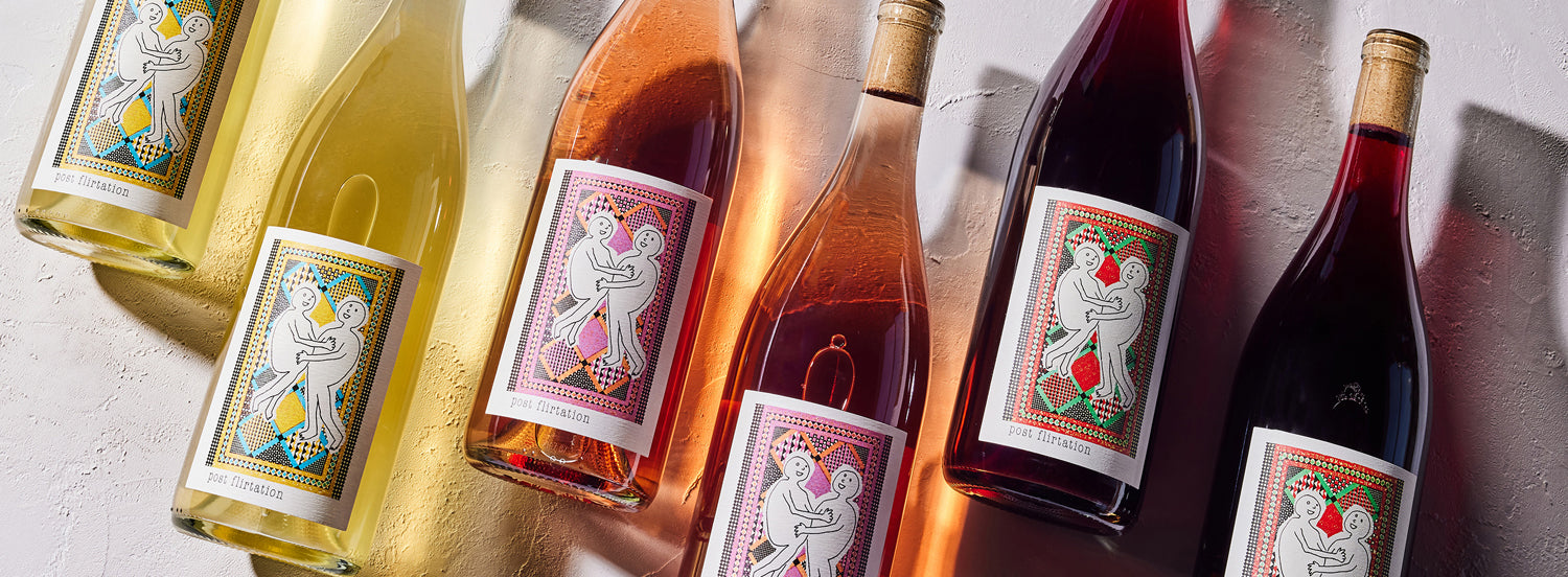 A collection of wine bottles with colorful, artistic labels featuring playful illustrations of figures.