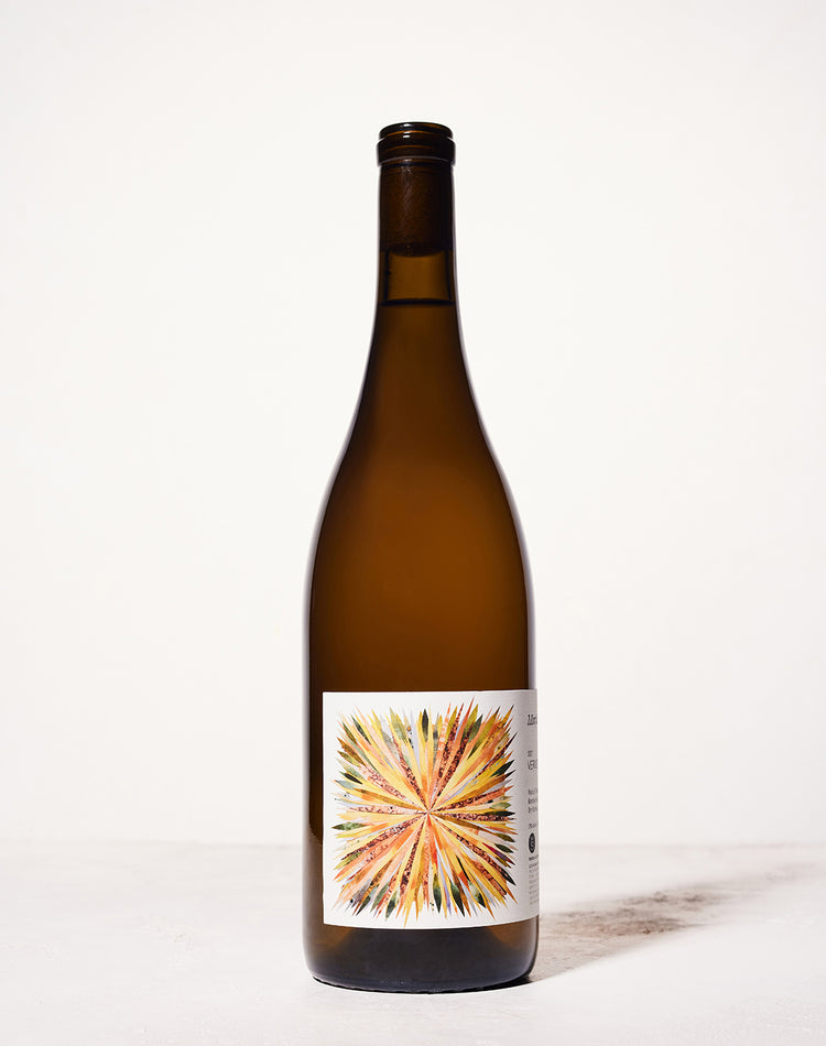 A brown wine bottle stands against a light background. The label features a colorful, sunburst design with vibrant orange, yellow, and green hues.