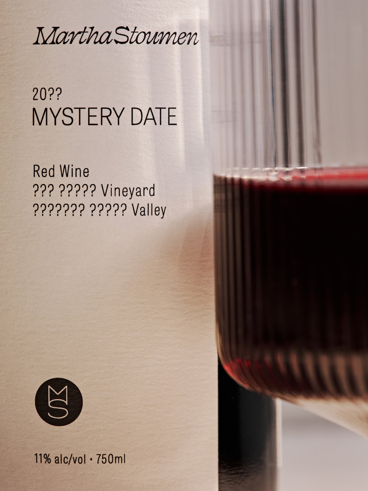 Wine label with a glass of red wine, featuring the brand 'Martha Stoumen' and text for a mystery wine release.