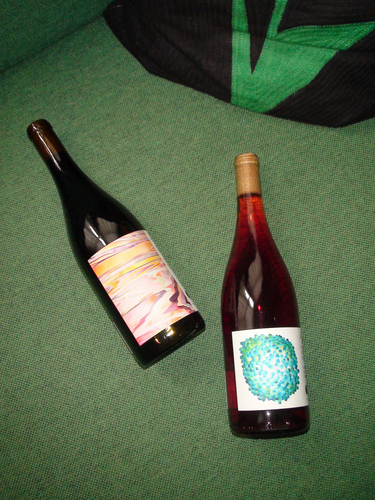 Two bottles of Martha Stoumen Wine sit on top of a green sofa.