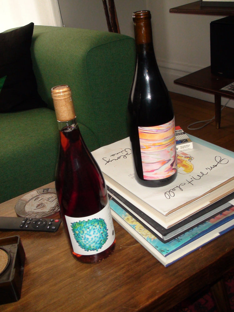 Two wine bottles on a table with a colorful label.