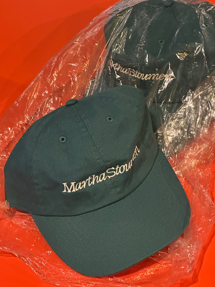 A teal cap with embroidered branding on top of an orange table