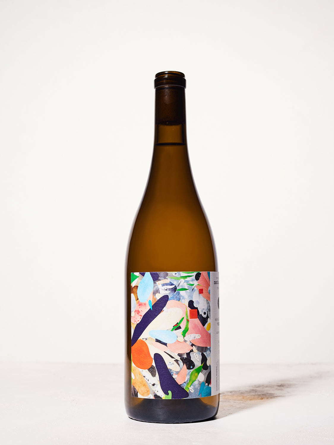 Brown glass wine bottle (Martha Stoumen out to the meadow) with a colorful label on a white background