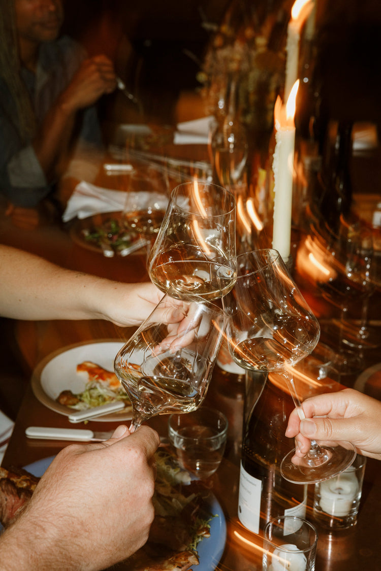 A set of three hands cheer over a dinner table