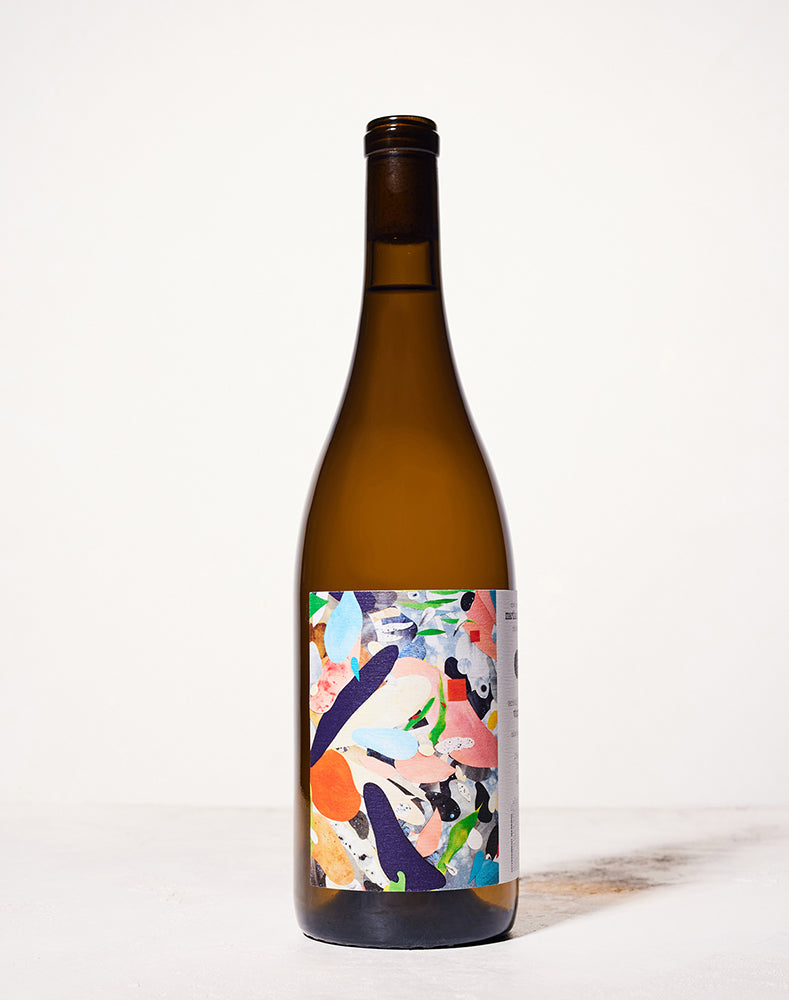 A tall brown wine bottle with a colorful abstract label featuring shapes in blue, pink, orange, and green, set against a plain white background.