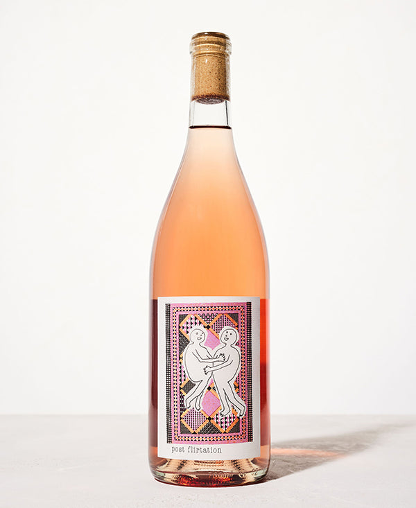 A bottle of rosé wine with a cork top, featuring a playful label of two abstract figures embracing, set against a geometric, colorful pattern.